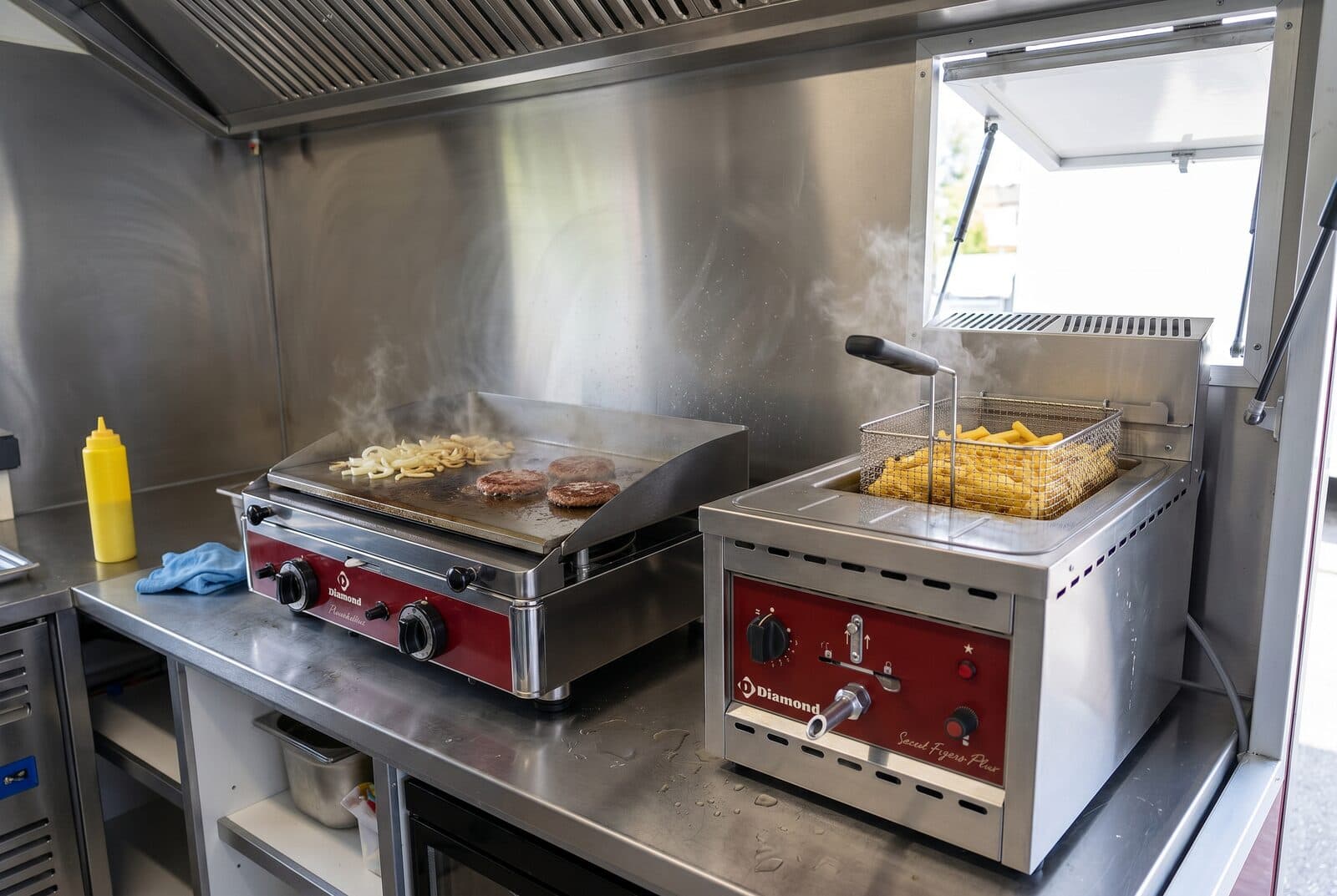 Professional griddle and fryer installed side by side in a food truck in service