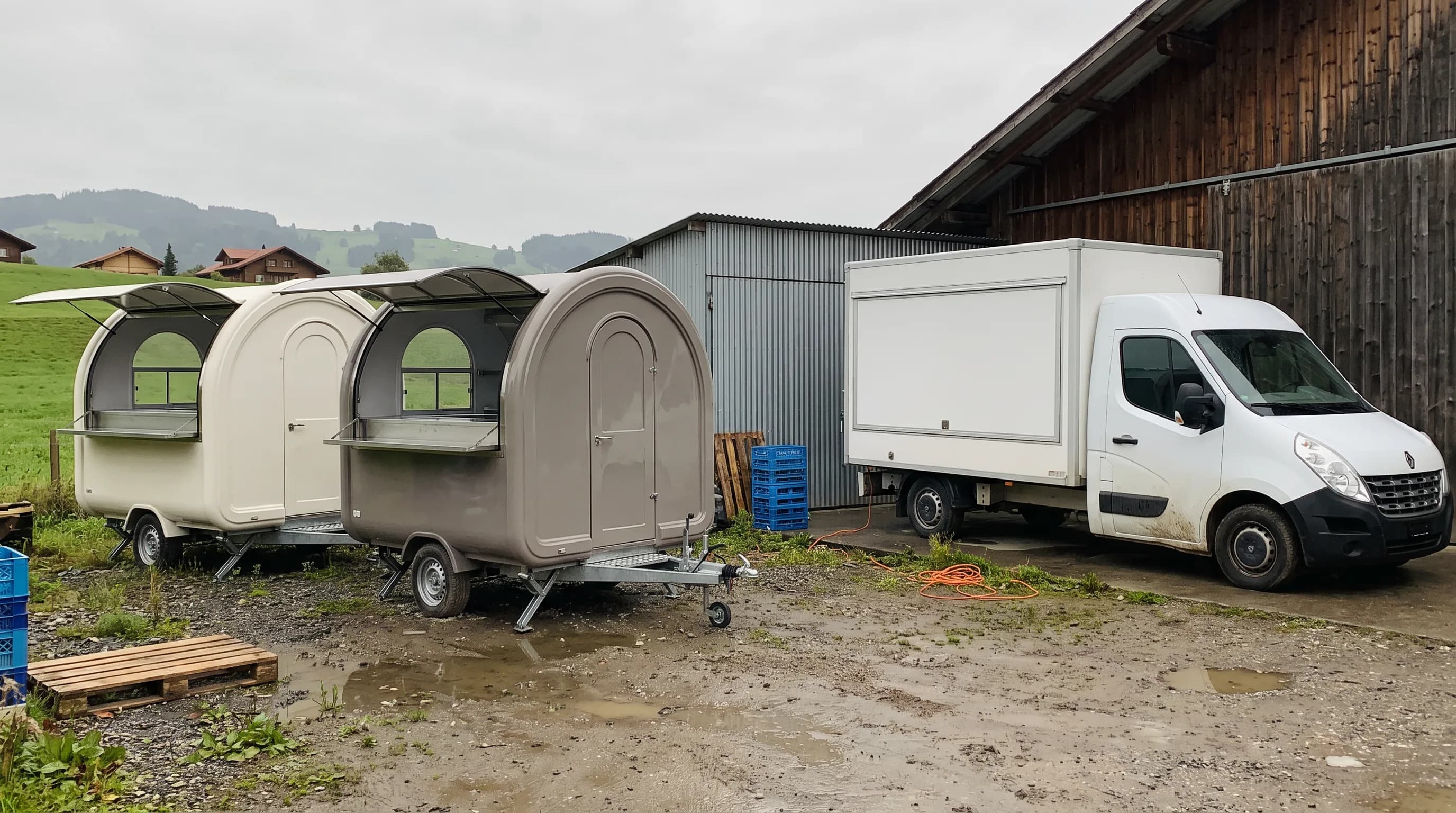 Deux remorques et un camion food truck stationnés dans une cour d'atelier en Suisse