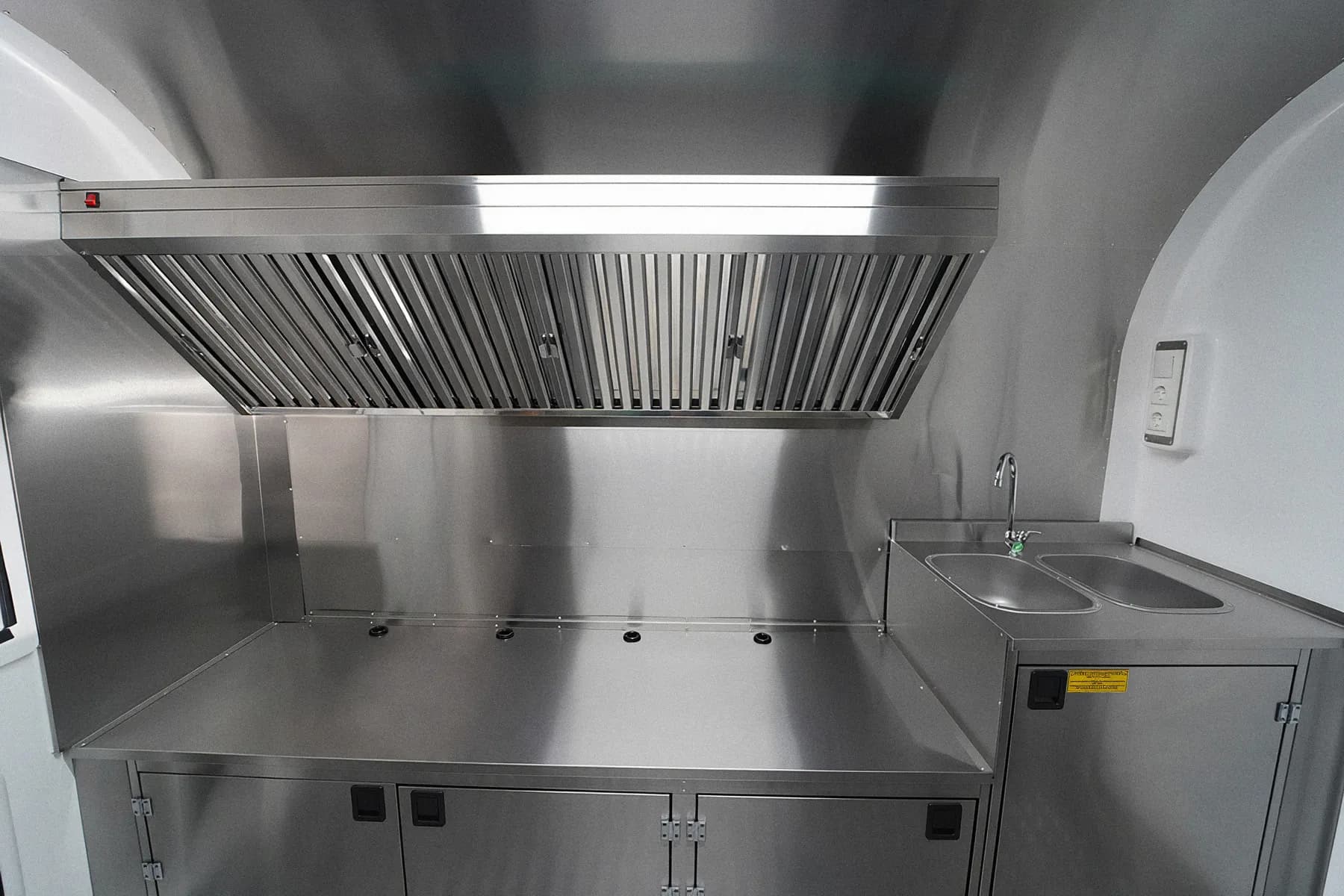 Hotte à extraction et fond inox au-dessus du plan de cuisson d'une remorque food truck